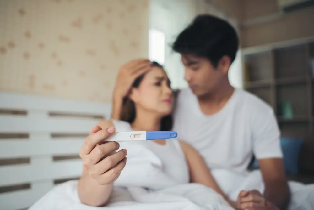 Couple holding positive pregnancy test feeling emotional about miscarriage risk in first pregnancy
